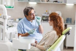 רופא שיניים מסביר למטופלת על אובדן שיניים ומראה לה