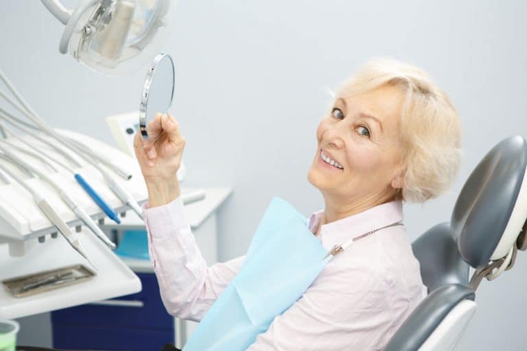 אישה מחייכת לאחר טיפול השתלת שיניים בשיטת אול און פור